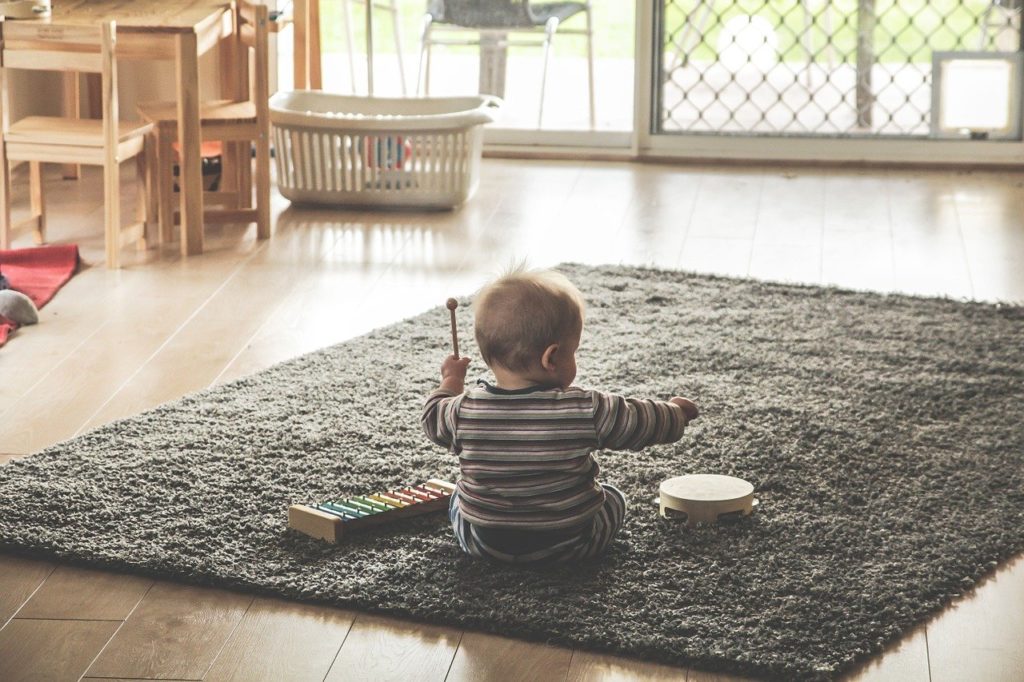 Bebé sentado jugando sobre una alfombra. 