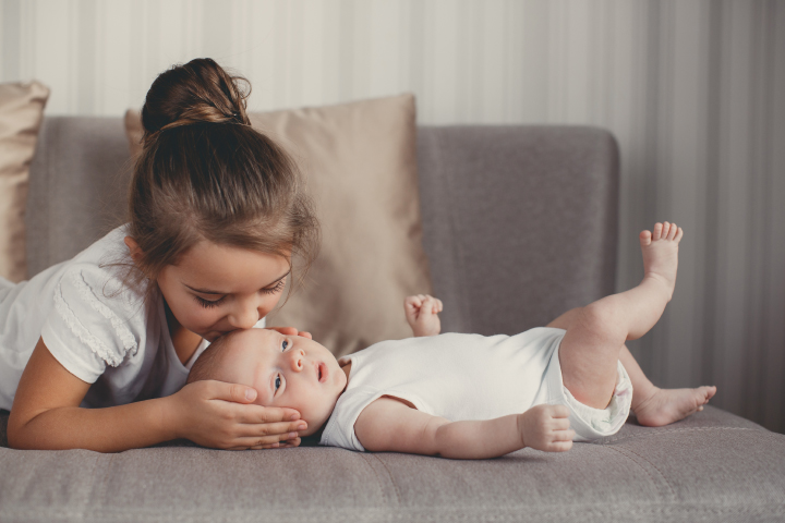 Nena besando a su hermanito nuevo